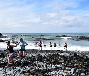 people running through kelp on a beach