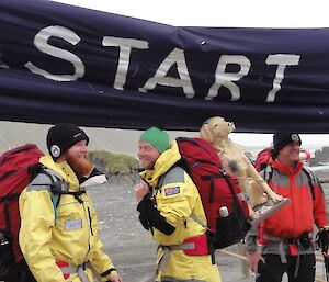 three people under a ‘start’ banner ready to begin a long trek with a dog mannequin