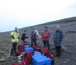 A group of people standing around some blue boxes while on a trek