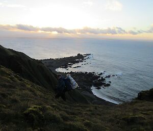 A man and Stay heading down a very steep hill to the beach