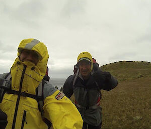 two men in wet weather clothes hiking