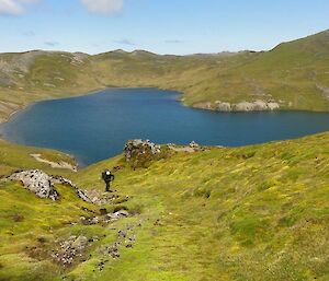 Mt Stibbs — a man coming up from Waterfall lake, which is surrounded by green vegetation.