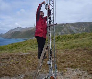 A man installing some equipment on a mast