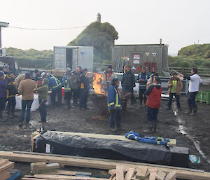 A group of people eat pizza around the fire