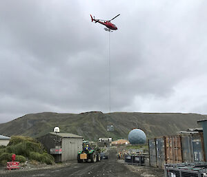 A helicopter flying over Macquarie Island station, during resupply operations.
