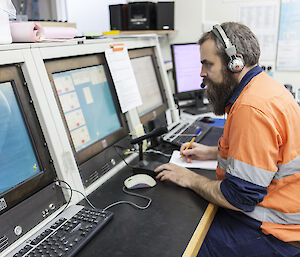 Man sitting at communications console wearing headphones