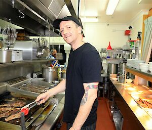 The chef Nick Baker standing cooking in the kitchen.