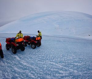 Three expeditioners on quad bikes on the sea ice.