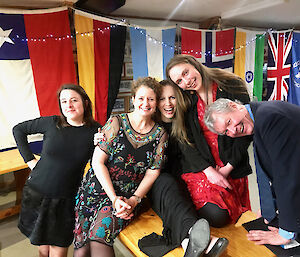 A group of people inside with flags behind them all smiling getting ready for midwinters dinner.