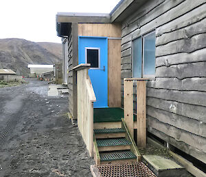 A photo of a wooden building with new steps and porch area.