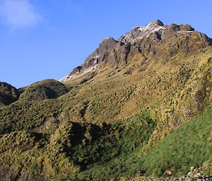 A small mountain with clear skies behind it.