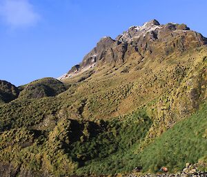 A small mountain with clear skies behind it.