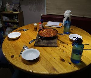 A pot of food in the middle of a table ready to be eaten.