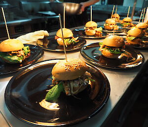 A table full of gourmet burgers on plates.