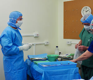 The doctor giving instructions to two of the lay surgical assistant.