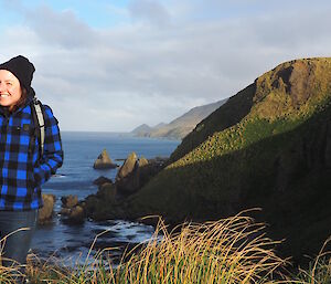 A women standing on top of a hill with water in the background.