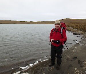 A man standing on the coastline with quite flat terrain around.