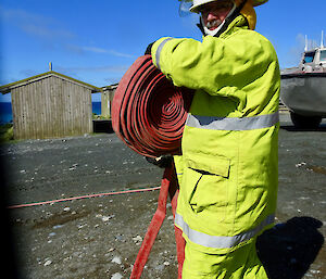 A man in a fire uniform unraveling a hose.