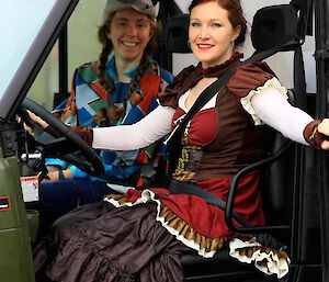 Two women sitting in a vehicle in fancy dress costumes.