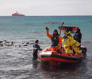 A group of French expeditioners land on the beach in a small watercraft.