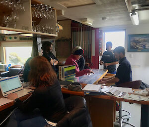 Group of people sitting at a wooden bar on computers and posting letters