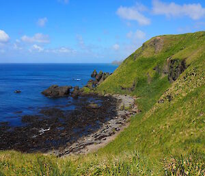 Water with a green hill in the foreground with steep banks.