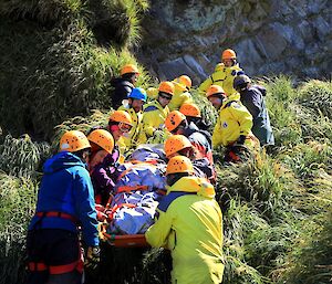 The rescue team carrying the stretcher over difficult terrain.