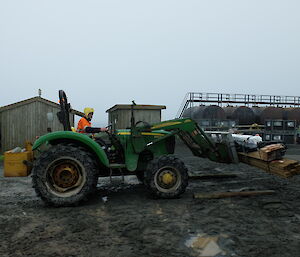 Lionel Whitehorn on a tractor removing a bundle of cargo from a LARC at the area behind the fuel tanks set aside as a biosecurity area on Macquarie Island