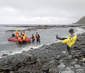 The last inflatable rubber boat leaves the island with the watercraft operators for the ship while SL Ali Dean kicks one leg into the air