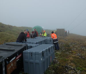 Expeditioners investigate the contents of several large containers that form the tsunami cache on Wireless Hill