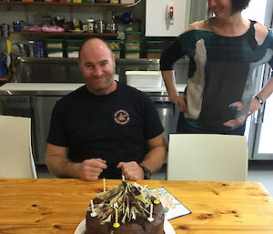 Tim Kerr and Cathryn O'Sullivan admire Tim’s large chocolate iced and chocolate decorated birthday cake