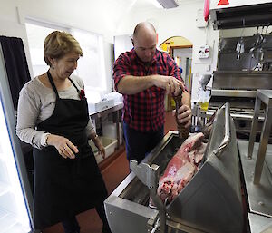 Tim Kerr seasoning the spit roast while Annette Fear our chef looks on