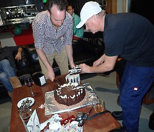 Jeremy Bird cutting his birthday cake and Peter Lecompte helping to serve
