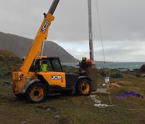 The new anemometer mast is raised at Macquarie Island with the help of the JCB telehandler