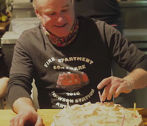 Peter with his birthday treat taking the candles out and getting ready to slice and serve