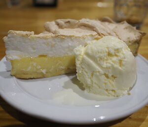 A plate containing a slice of lemon meringue pie and a scoop of icecream