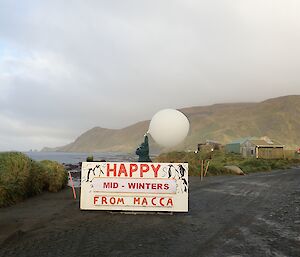 A met balloon is released behibd the Macca noticeboard which states Happy Midwinters