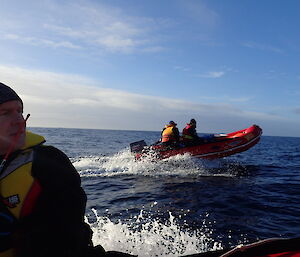 A view from one IRB on the water to another while heading south to Waterfall Bay on Macquarie Island. Rchard Youd is visible in one boat and Greg, Jez and Danielle are visible in the other.