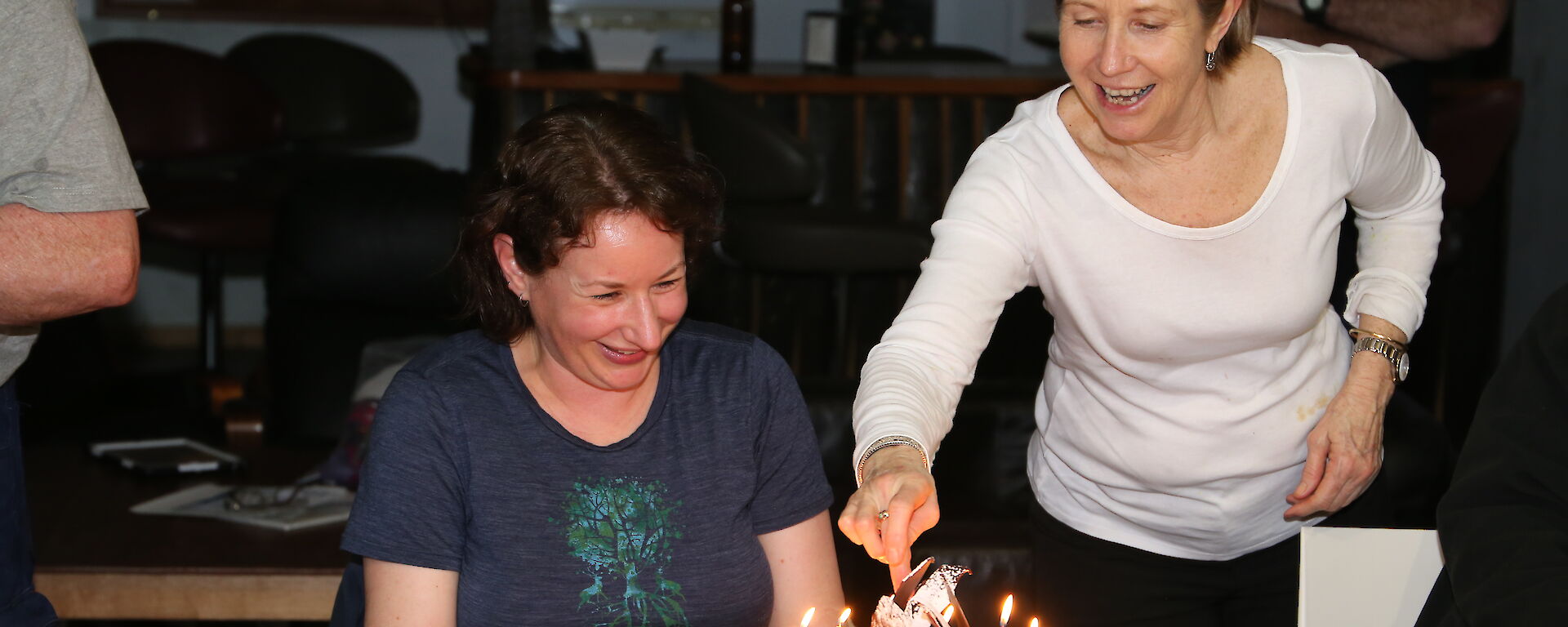 Annette Fear lights the candles on a birthday cake while the recipient Vicki Heinrich looks on