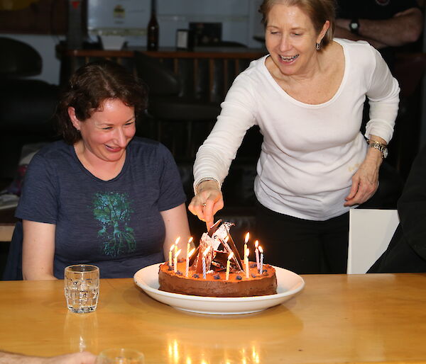 Annette Fear lights the candles on a birthday cake while the recipient Vicki Heinrich looks on