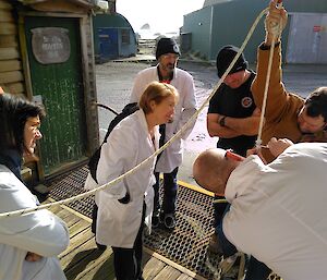 Rich Youd demonstrates the strength of climbing rope on the porch at Macca to a group of expeditioners during a Science Smoko