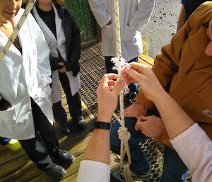 Rich cutting through the core of a length of climbing rope under tension to illustrate its strength even when partially cut on the porch outside the mess at Macca