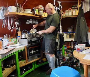 An expeditioner cooking something tasty at Brothers Point Hut.