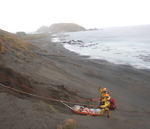 Jez, Greg and stretcher-bound Angus nearly at the bottom of the slope and onto the beach in the recent SAR exercise on Macca