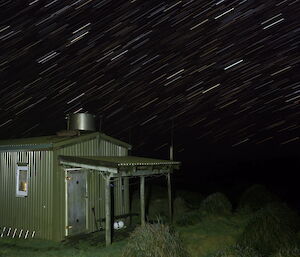 A night shot of Bauer Bay with the hut in the foreground and star trails above