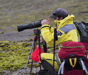 Chris Burns taking a photo in the field using a camera with large lens on a tripod