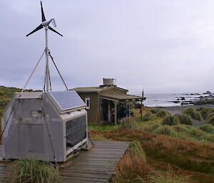 A picture of the Bauer Bay RAPS unit showing all the features including the solar panel, wind turbine, regulators, and visual access — plus the fantastic view at Bauer Bay