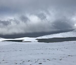 A snowy view on the Varne Plateau with a lake reflecting the grey skies