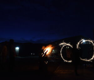 Expeditioners waving sparklers around on Guy Fawkes night near a bonfire in a drum