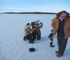 Fishing team drilling a hole in the sea ice